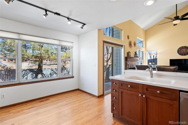 3151 E 134th Cir, Thornton, CO 80241 - kitchen featuring a sink, track lighting, a brick fireplace, light wood-style flooring, and stainless steel dishwasher