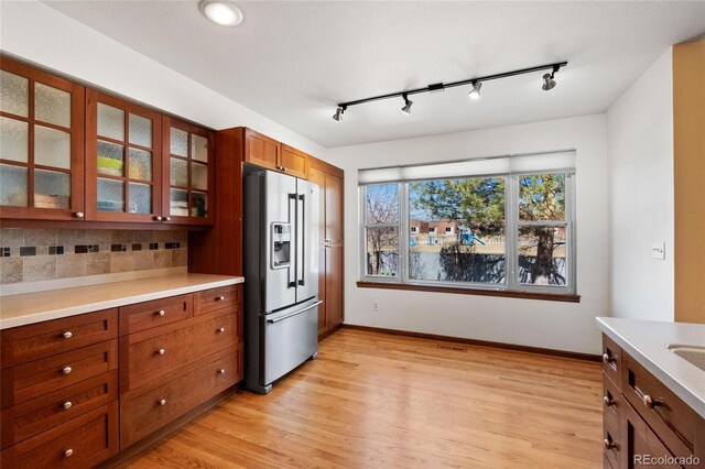 3151 E 134th Cir, Thornton, CO 80241 - kitchen featuring stainless steel refrigerator with ice dispenser, decorative backsplash, track lighting, and glass insert cabinets