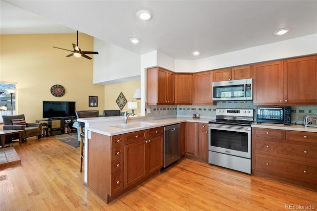 3151 E 134th Cir, Thornton, CO 80241 - kitchen with appliances with stainless steel finishes, a sink, open floor plan, brown cabinetry, and vaulted ceiling