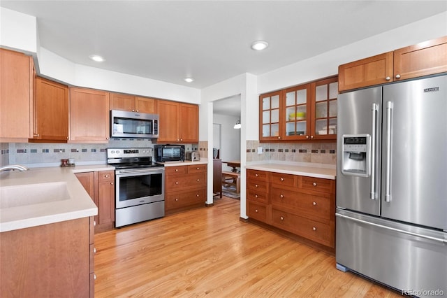 3151 E 134th Cir, Thornton, CO 80241 - kitchen with stainless steel appliances, a sink, backsplash, light wood-style flooring, and light countertops