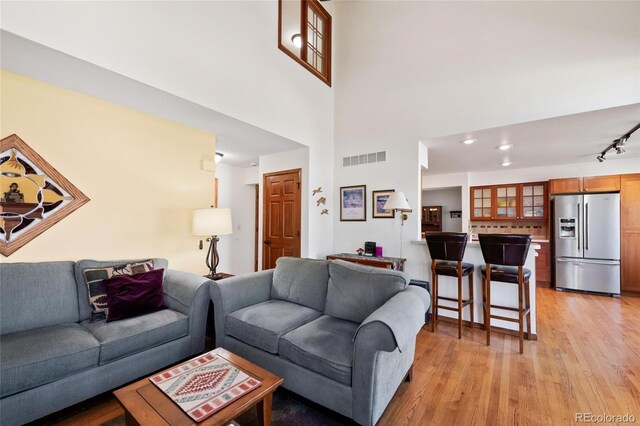 3151 E 134th Cir, Thornton, CO 80241 - living room featuring light wood finished floors, rail lighting, and a high ceiling