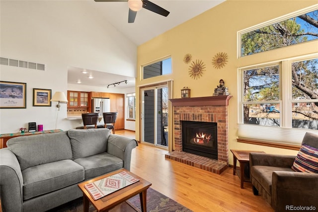 3151 E 134th Cir, Thornton, CO 80241 - living area with high vaulted ceiling, light wood-type flooring, a brick fireplace, and ceiling fan