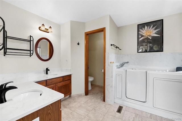 3151 E 134th Cir, Thornton, CO 80241 - full bath with vanity, toilet, a bath, tile patterned floors, and tile walls