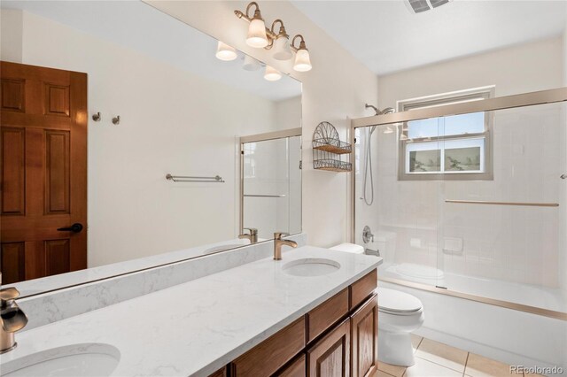 3151 E 134th Cir, Thornton, CO 80241 - bathroom featuring double vanity, toilet, combined bath / shower with glass door, and tile patterned floors