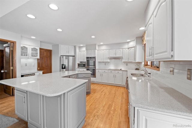 4161 W Lake Cir N, Littleton, CO 80123 - kitchen featuring stainless steel appliances, a sink, a kitchen island, light wood-style flooring, and white cabinets