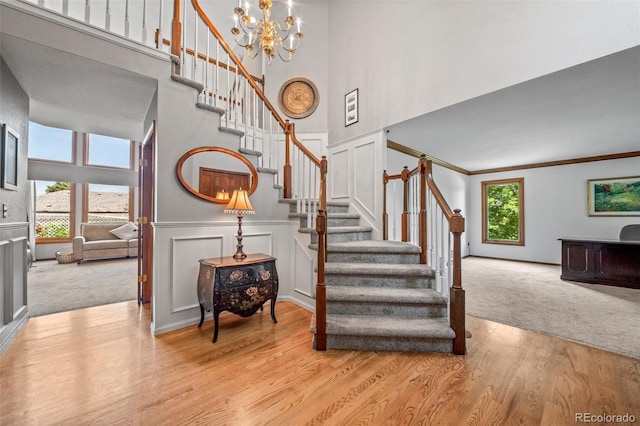 4161 W Lake Cir N, Littleton, CO 80123 - stairs with a towering ceiling, wood finished floors, a chandelier, a decorative wall, and carpet