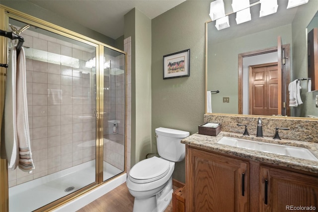 4161 W Lake Cir N, Littleton, CO 80123 - full bathroom featuring toilet, vanity, a shower stall, a textured wall, and wood finished floors