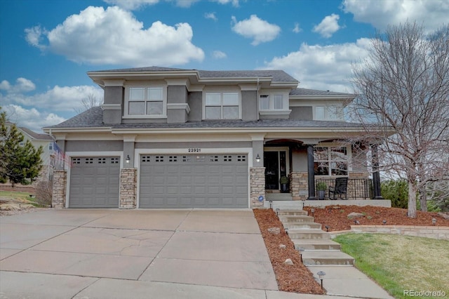 prairie-style house with stone siding, concrete driveway, stucco siding, an attached garage, and a porch