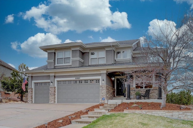 prairie-style home featuring stone siding, a garage, concrete driveway, stucco siding, and covered porch