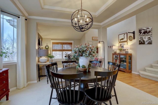 dining area featuring a tray ceiling, light wood-type flooring, a healthy amount of sunlight, and a notable chandelier