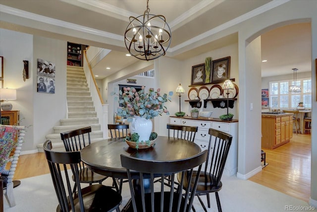 dining area featuring arched walkways, light wood-style floors, and a chandelier