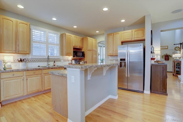 kitchen with a sink, black microwave, stainless steel refrigerator with ice dispenser, and light brown cabinetry