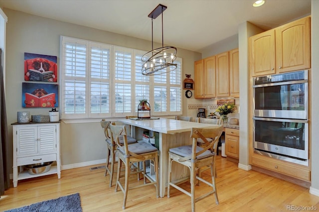 kitchen with light countertops, stainless steel double oven, an inviting chandelier, light wood-style floors, and light brown cabinets