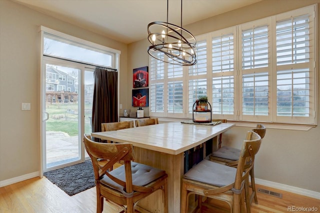 dining area with baseboards, light wood-style flooring, an inviting chandelier, and plenty of natural light