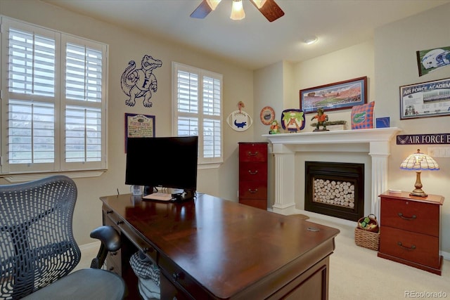 home office featuring baseboards, a fireplace, carpet flooring, and a ceiling fan