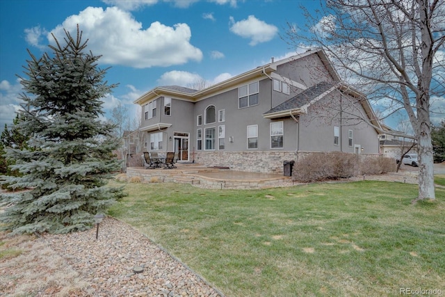 rear view of property featuring a lawn, stucco siding, a patio area, and stone siding