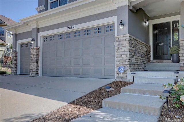 22921 E Euclid Cir, Aurora, CO 80016 - doorway to property featuring stone siding, stucco siding, concrete driveway, and an attached garage
