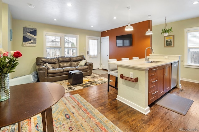 kitchen with open floor plan, a sink, pendant lighting, light countertops, and dishwasher