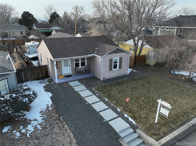 single story home featuring a shingled roof, a front yard, a residential view, and fence