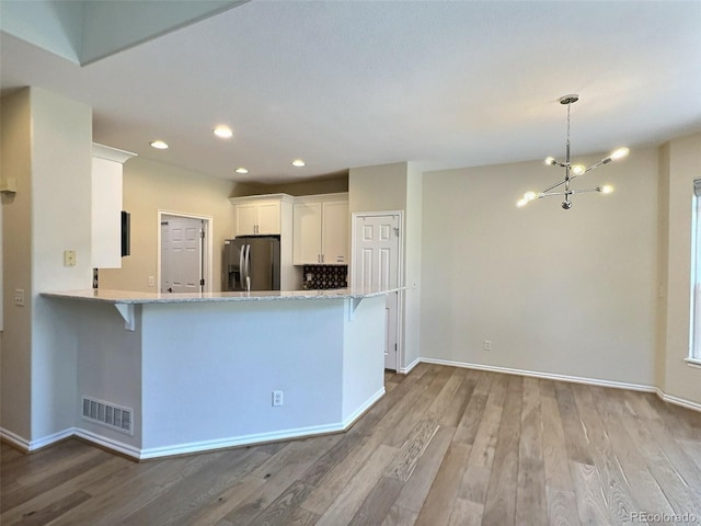 3000 E 112th Ave Unit 102, Northglenn, CO 80233 - kitchen featuring stainless steel fridge, light wood-style floors, a chandelier, a breakfast bar area, and recessed lighting