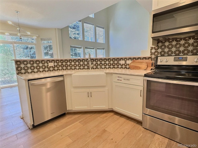 3000 E 112th Ave Unit 102, Northglenn, CO 80233 - kitchen featuring stainless steel appliances, light wood finished floors, white cabinetry, decorative backsplash, and a peninsula