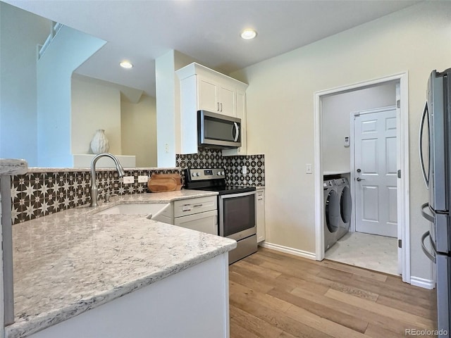 3000 E 112th Ave Unit 102, Northglenn, CO 80233 - kitchen featuring stainless steel appliances, separate washer and dryer, light wood-type flooring, white cabinets, and decorative backsplash