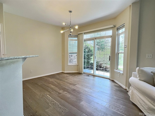 3000 E 112th Ave Unit 102, Northglenn, CO 80233 - unfurnished dining area with healthy amount of natural light, dark wood-type flooring, and a chandelier