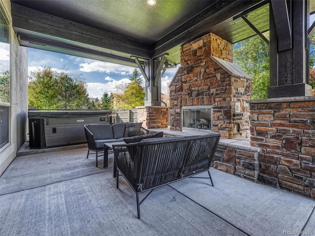 view of patio / terrace featuring an outdoor living space with a fireplace and a hot tub