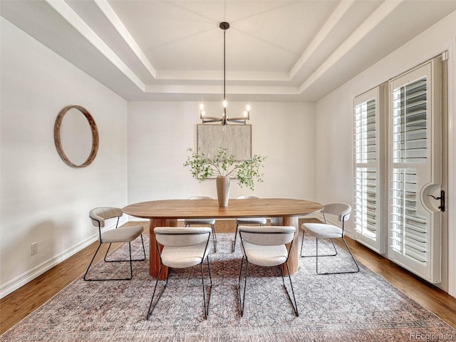 dining room featuring hardwood / wood-style floors, an inviting chandelier, and a tray ceiling