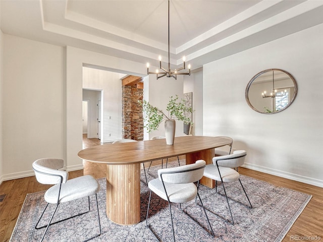 dining area featuring a notable chandelier, hardwood / wood-style floors, and a tray ceiling