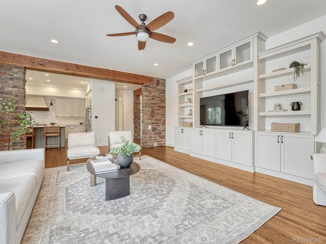 living room featuring built in features, light hardwood / wood-style flooring, and ceiling fan