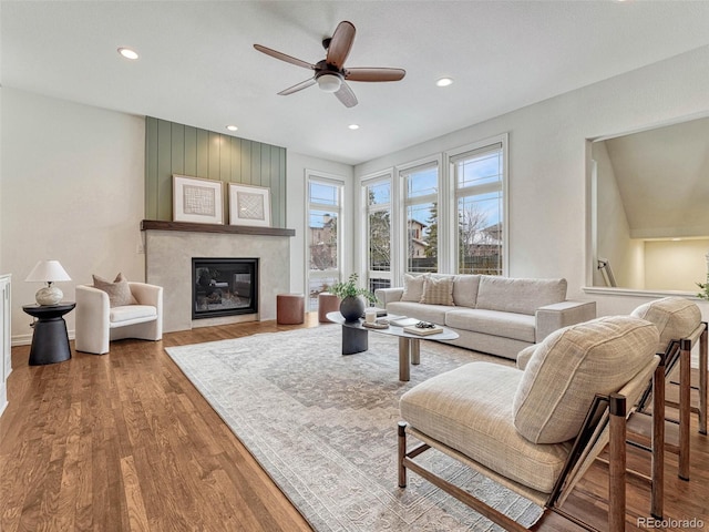 living room featuring hardwood / wood-style flooring, a large fireplace, and ceiling fan