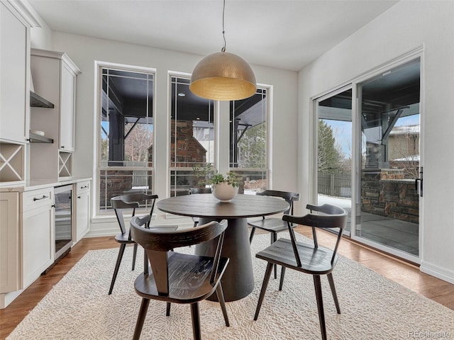 dining area with light hardwood / wood-style flooring and beverage cooler