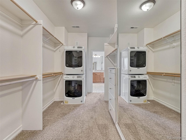 walk in closet with light carpet and stacked washing maching and dryer