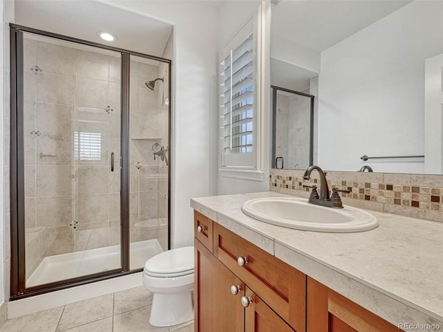 bathroom with toilet, tasteful backsplash, walk in shower, tile patterned flooring, and vanity