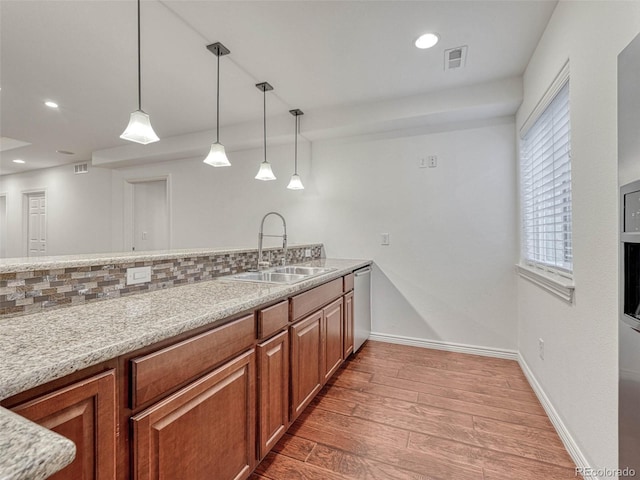 kitchen with hanging light fixtures, stainless steel dishwasher, sink, light wood-type flooring, and backsplash