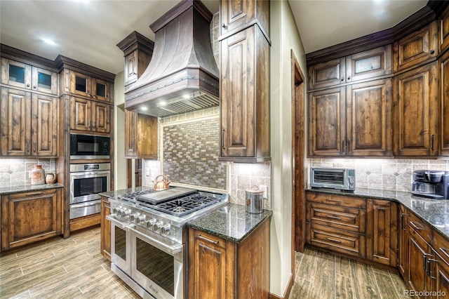 25735 County Road 295, Nathrop, CO 81236 - kitchen featuring appliances with stainless steel finishes, custom exhaust hood, a warming drawer, backsplash, and dark stone countertops