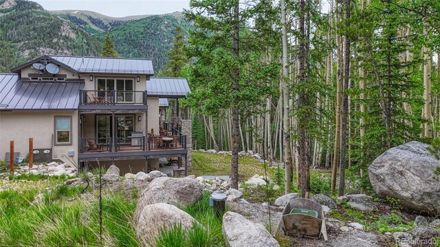 25735 County Road 295, Nathrop, CO 81236 - rear view of house featuring a standing seam roof, stucco siding, a balcony, and a metal roof