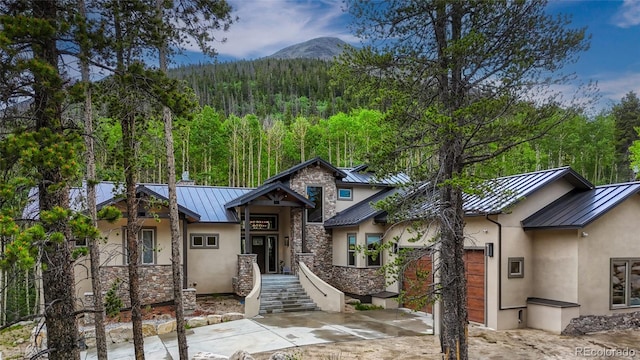 25735 County Road 295, Nathrop, CO 81236 - view of front facade featuring a standing seam roof, stucco siding, a metal roof, a wooded view, and stone siding