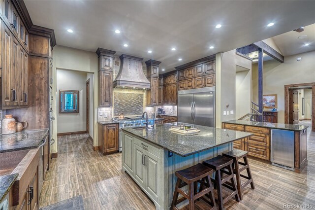 25735 County Road 295, Nathrop, CO 81236 - kitchen featuring built in refrigerator, premium range hood, an island with sink, tasteful backsplash, and a kitchen bar