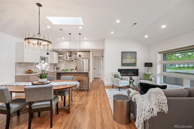 2998 S Adams St, Denver, CO 80210 - living room featuring vaulted ceiling, a skylight, a chandelier, a glass covered fireplace, and recessed lighting