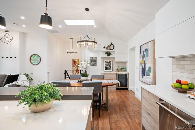 2998 S Adams St, Denver, CO 80210 - dining area featuring beverage cooler, a skylight, lofted ceiling, wood finished floors, and a chandelier