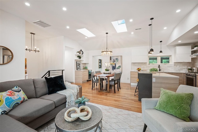2998 S Adams St, Denver, CO 80210 - living area with a chandelier, light wood-type flooring, a skylight, vaulted ceiling, and recessed lighting