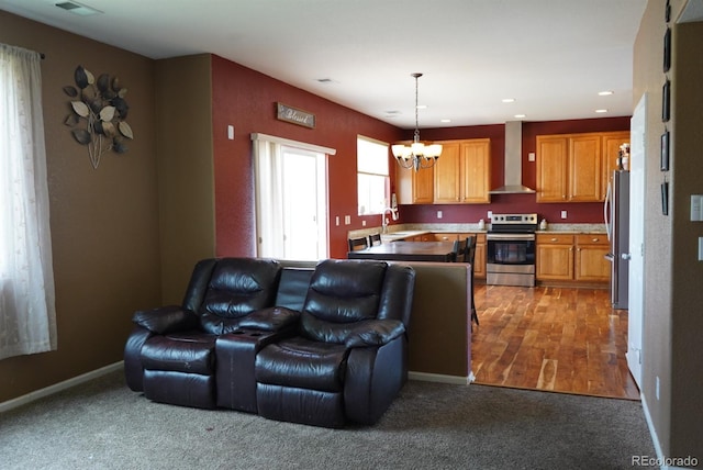 9616 Nucla St, Commerce City, CO 80022 - kitchen featuring stainless steel appliances, wall chimney range hood, open floor plan, a chandelier, and carpet