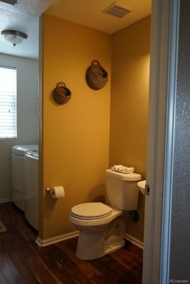 9616 Nucla St, Commerce City, CO 80022 - bathroom featuring washing machine and clothes dryer, wood finished floors, toilet, and baseboards