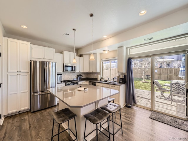 kitchen featuring appliances with stainless steel finishes, a breakfast bar area, a sink, and decorative backsplash