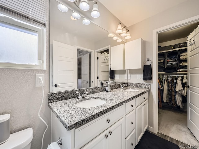 bathroom with a sink, a spacious closet, toilet, and double vanity