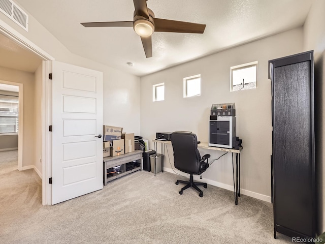 carpeted home office with ceiling fan, visible vents, and baseboards