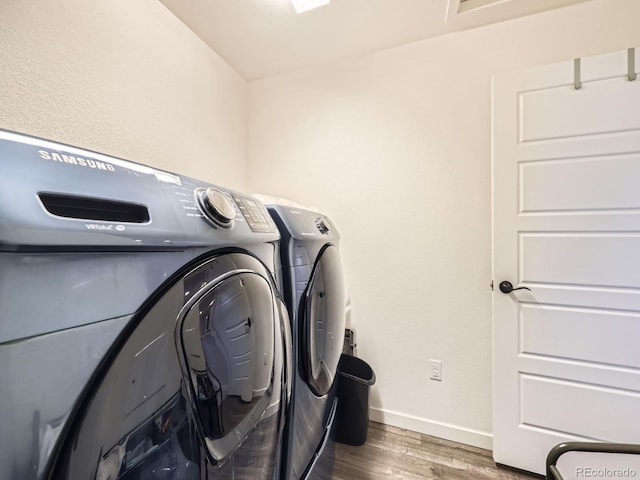 washroom featuring laundry area, baseboards, wood finished floors, and washing machine and clothes dryer