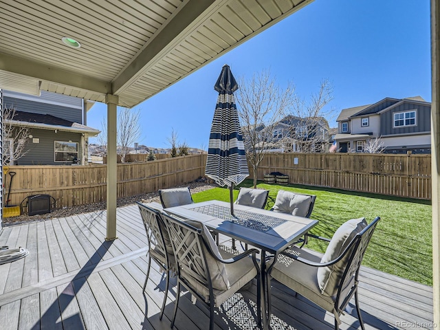 wooden terrace with outdoor dining area, a fenced backyard, and a lawn